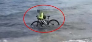 Coronavirus, ciclista entra in mare con la sua bici per evitare il controllo